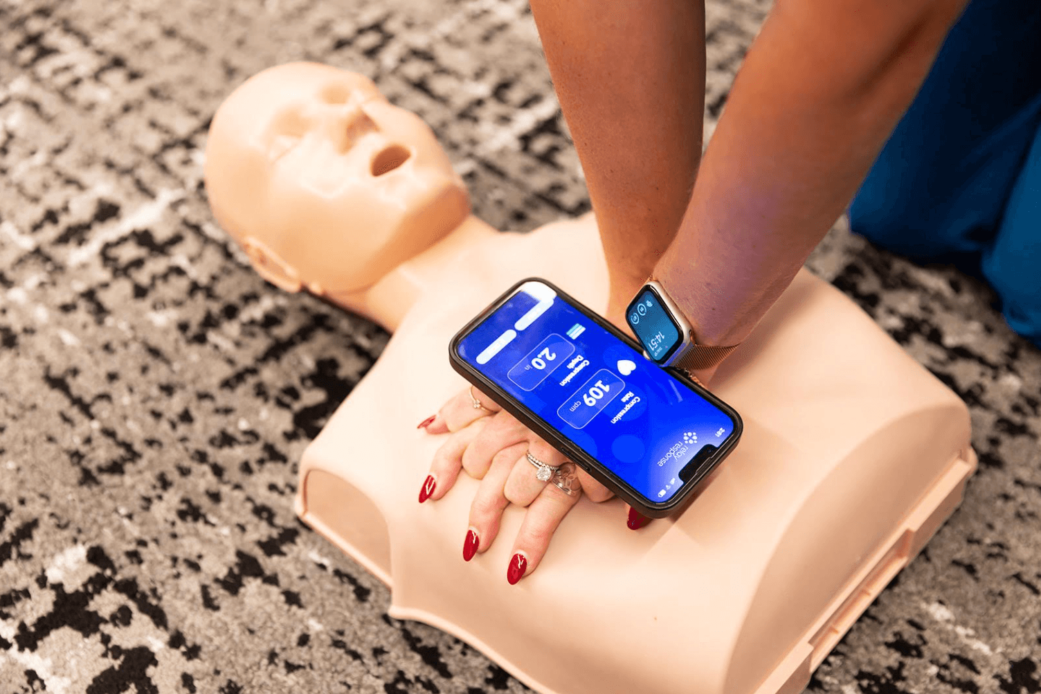 Hands performing CPR compressions alongside the Ready Response app and smartwatch